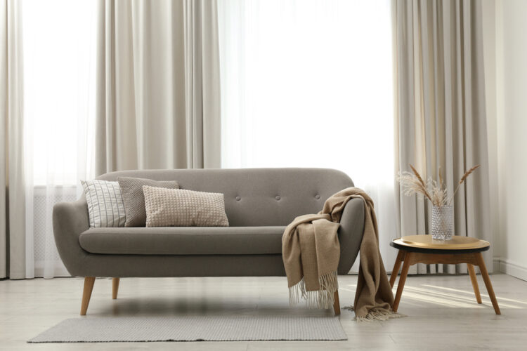 Grey,Sofa,With,Pillows,Near,Window,In,Stylish,Living,Room